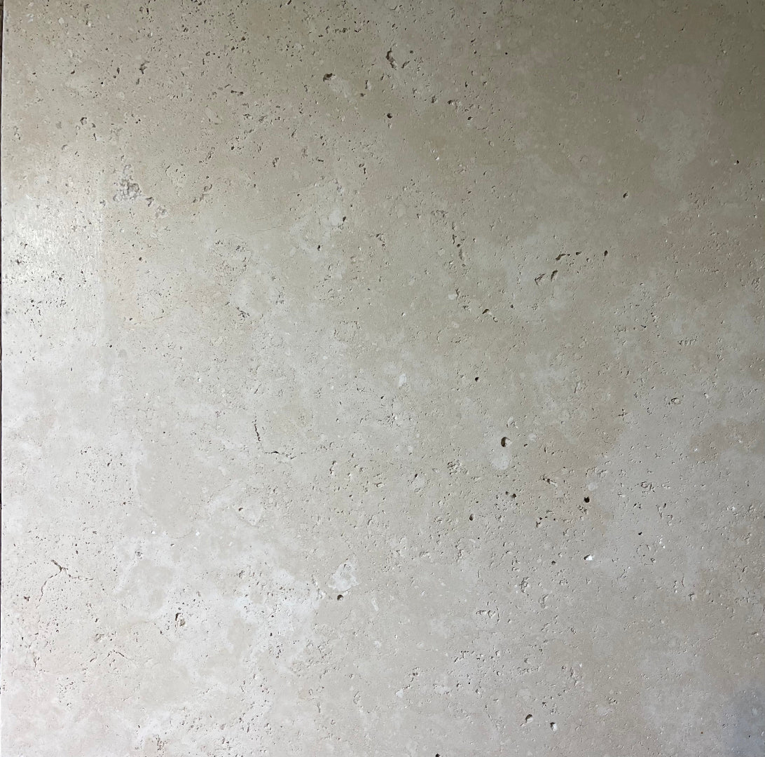 Tumbled natural stone tiles in travertine and marble, featuring soft edges and textured, rustic finish