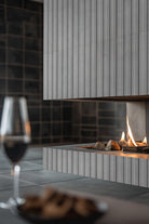 Sinfonia Hip Hop Ceniza Fluted Tiles installed on modern fireplace wall with seamless, elegant finish