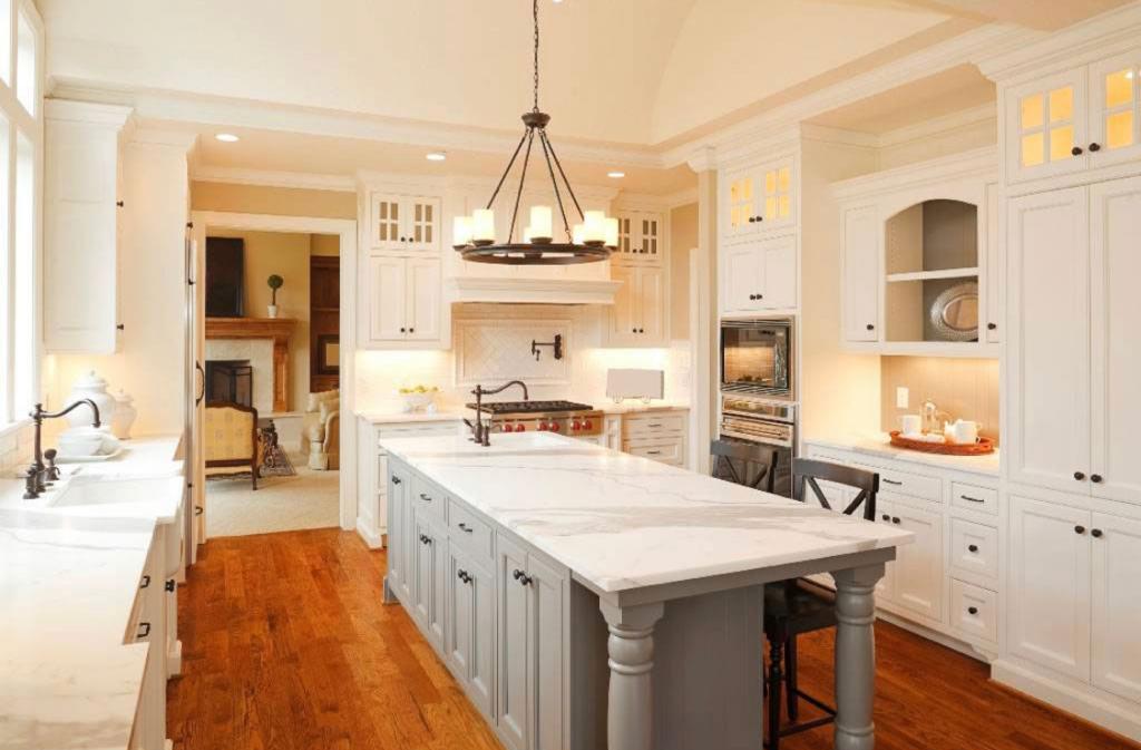 Calacatta Gold marble countertops in a bright traditional kitchen with white cabinetry and hardwood floors