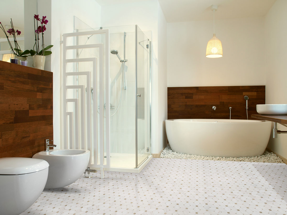 Natural stone mosaic tile installed on shower floor with soft white and gray tones