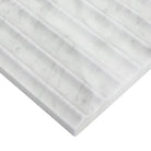 Edge of Carrara White marble showing inverted fluted surface and soft gray veining