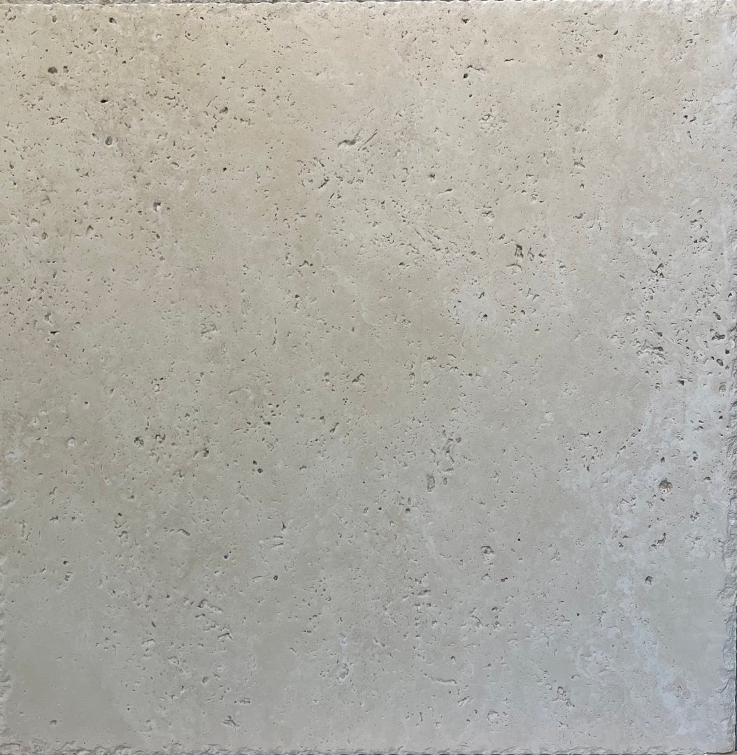 Close-up of Ivory Travertine 18x18 tile showing brushed surface and chiseled edge