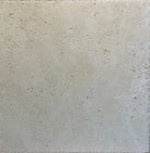 Close-up of Ivory Travertine 18x18 tile showing brushed surface and chiseled edge