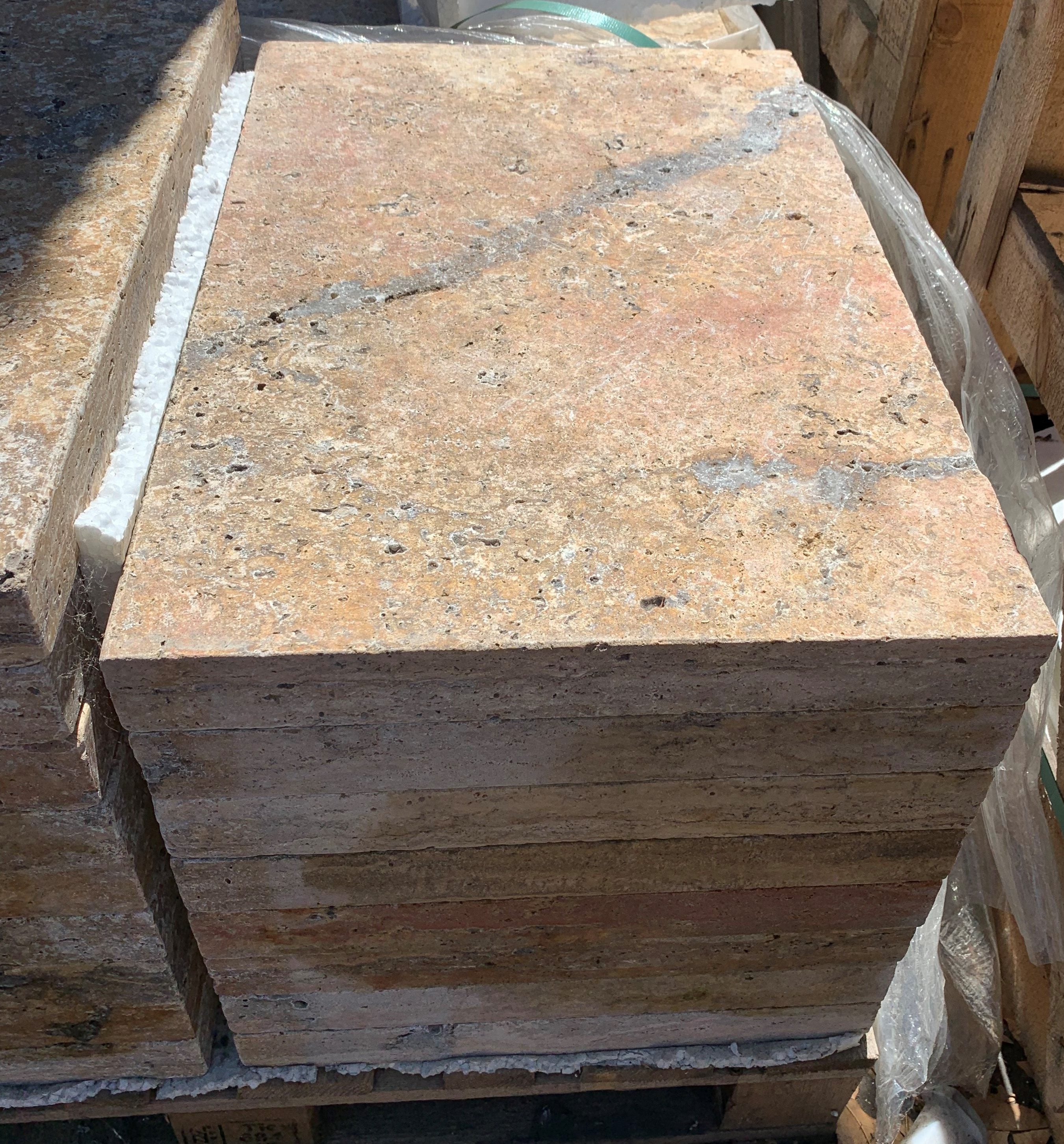 Close-up of Autumn Travertine showing burgundy and cream veining with straight-cut edge