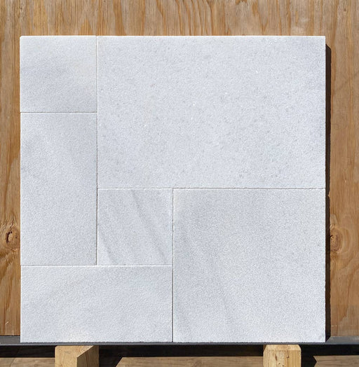 Close-up of Bianco Carrara Marble showing textured leathered finish and subtle veining