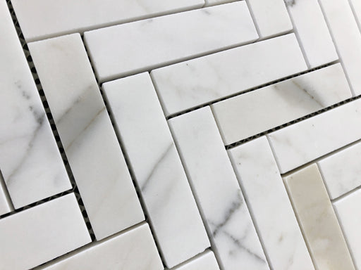 Close-up of Calacatta Gold marble tiles with white base and gold veining in 1x3 herringbone layout