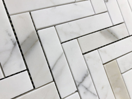 Close-up of Calacatta Gold 1x4 marble tiles in herringbone layout with gold veining