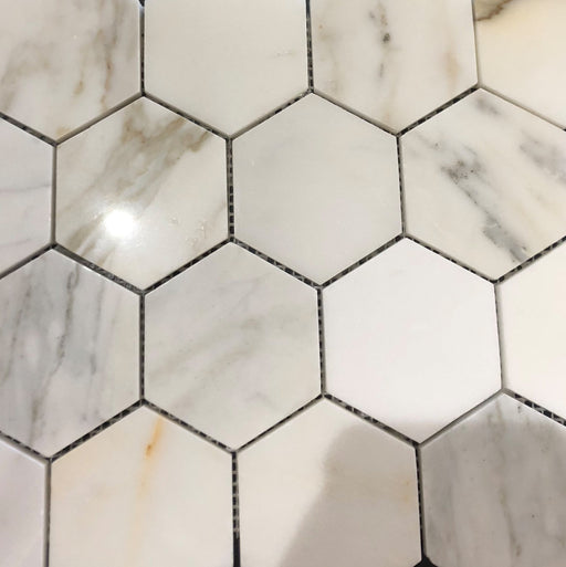 Close-up of Calacatta Gold 3-inch hex tile showing veining and polished surface