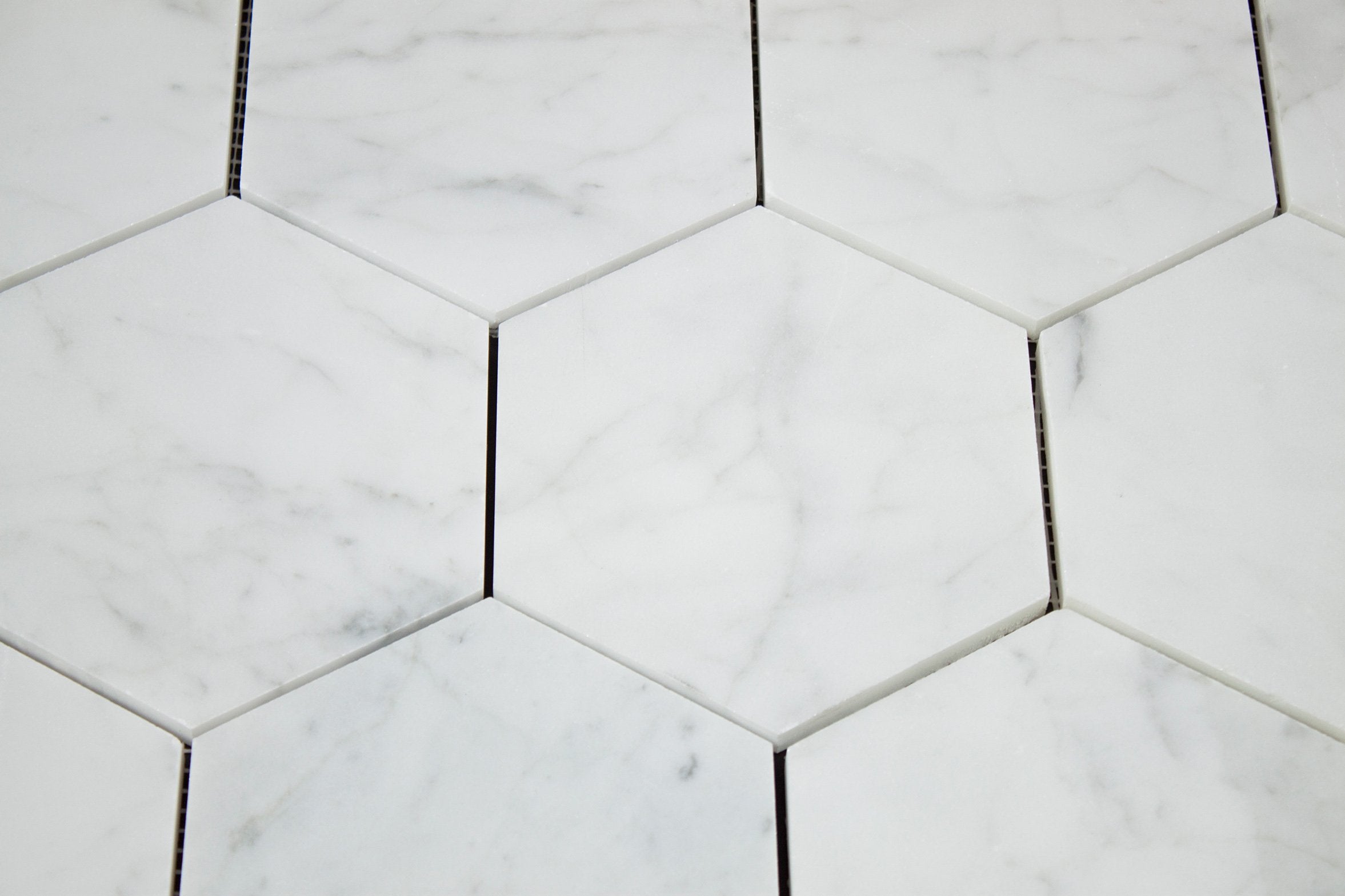 Close-up of Carrara White hex tile showing gray veining and polished surface