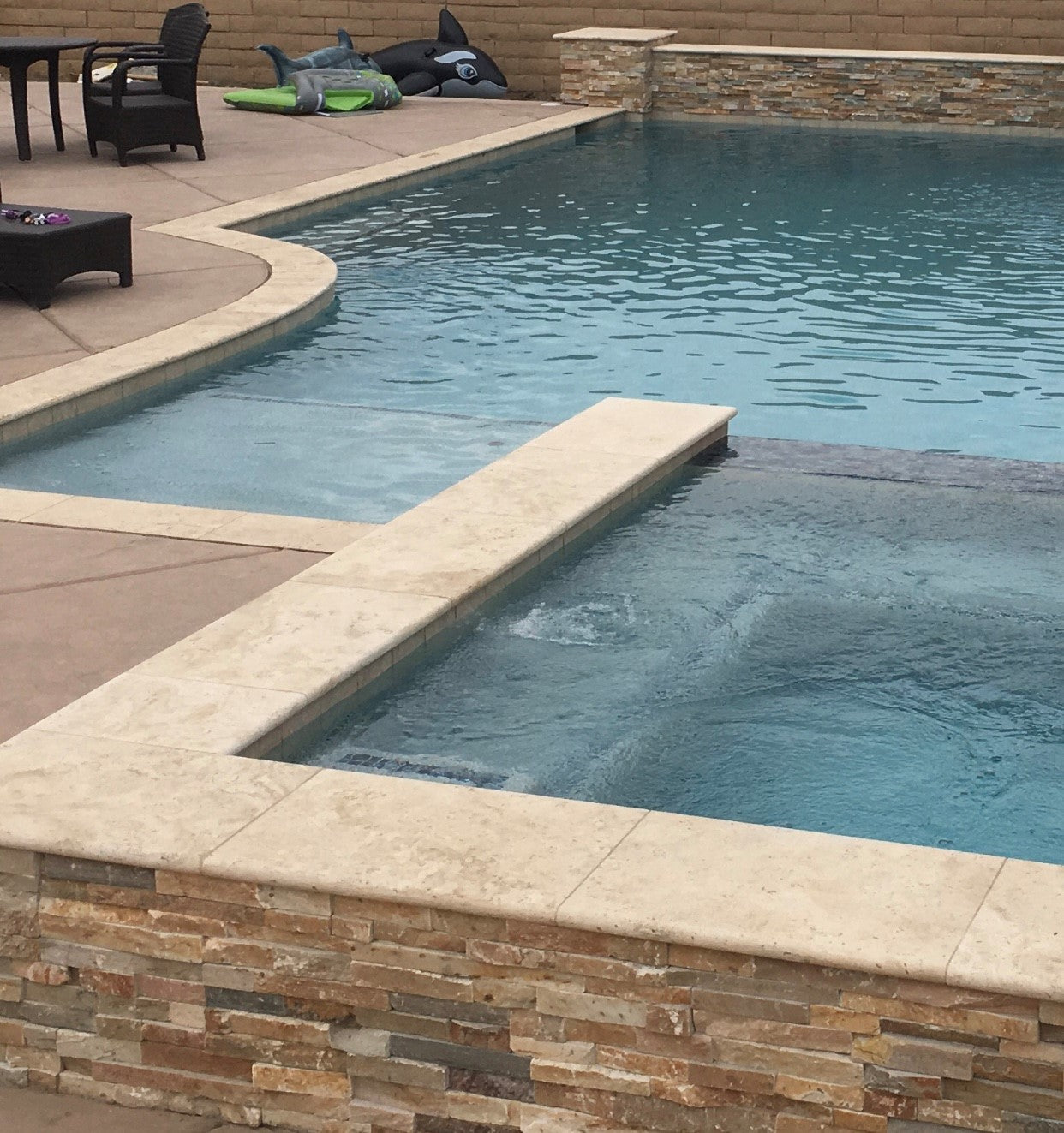 Cordoba Cream Travertine Coping installed around poolside deck with beige stone accents