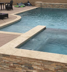 Cordoba Cream Travertine Coping installed around poolside deck with beige stone accents