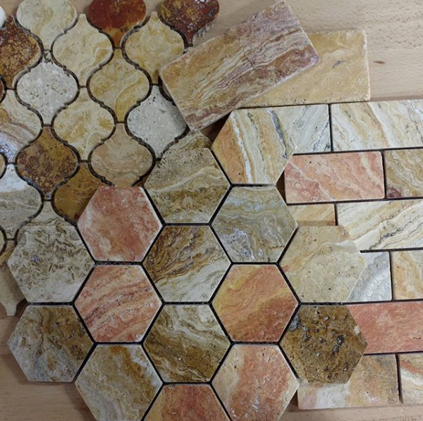 Close-up view of 2x2 tumbled Scabos Travertine showing rich red, gold, and cream colors