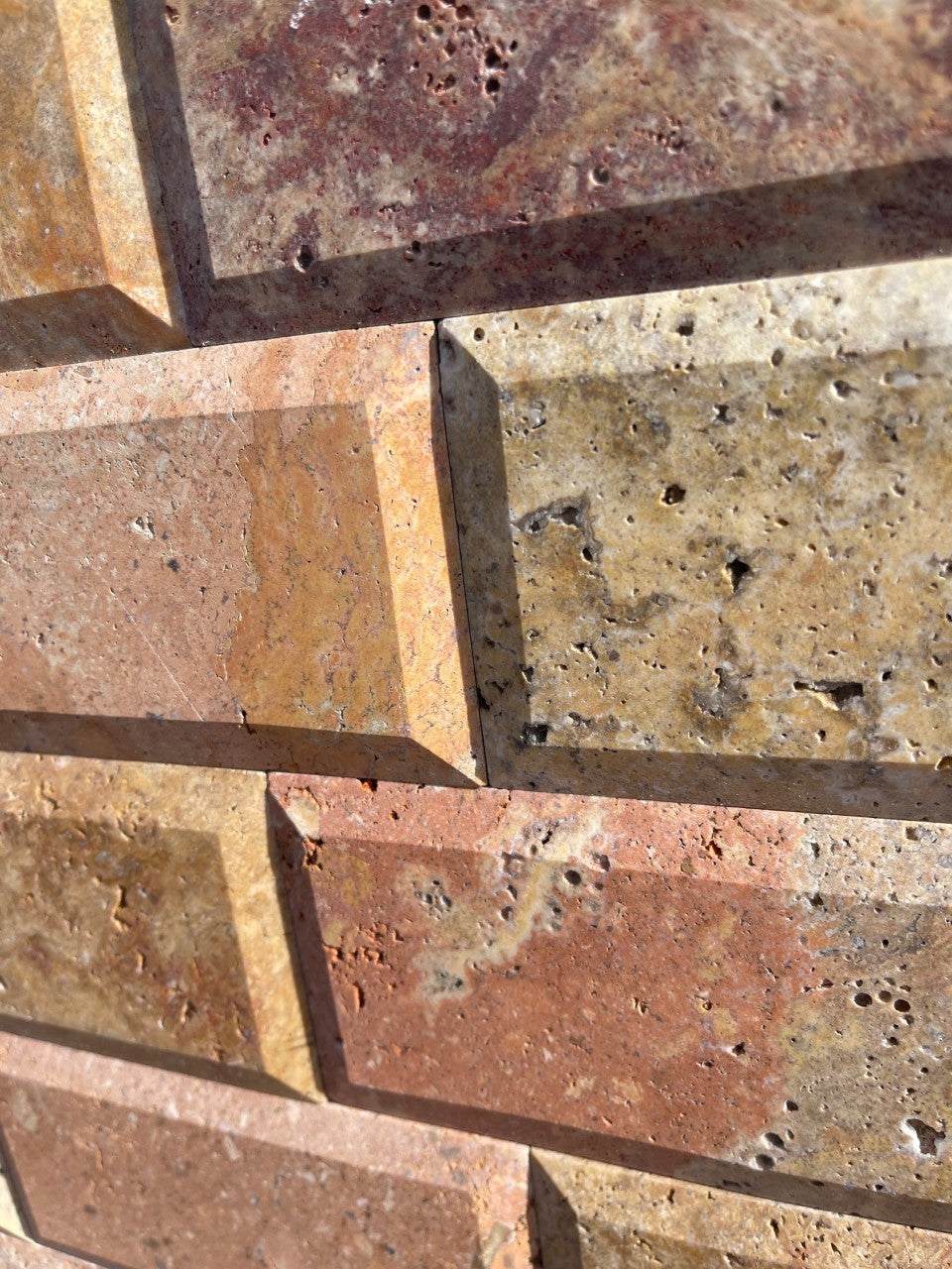Close-up of Scabos 3x6 Travertine showing beveled profile and vibrant color blend
